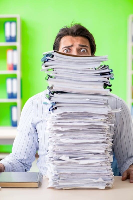 Muž zavalený papíry